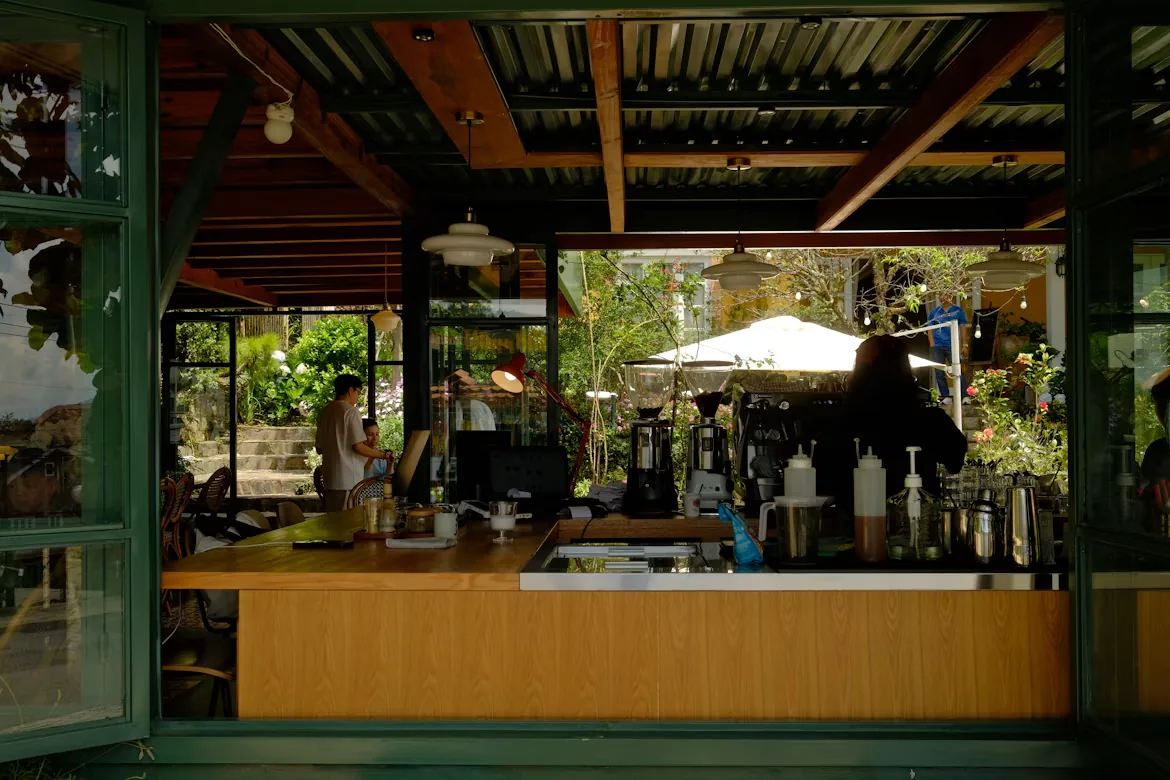 A barista pouring coffee among the plants